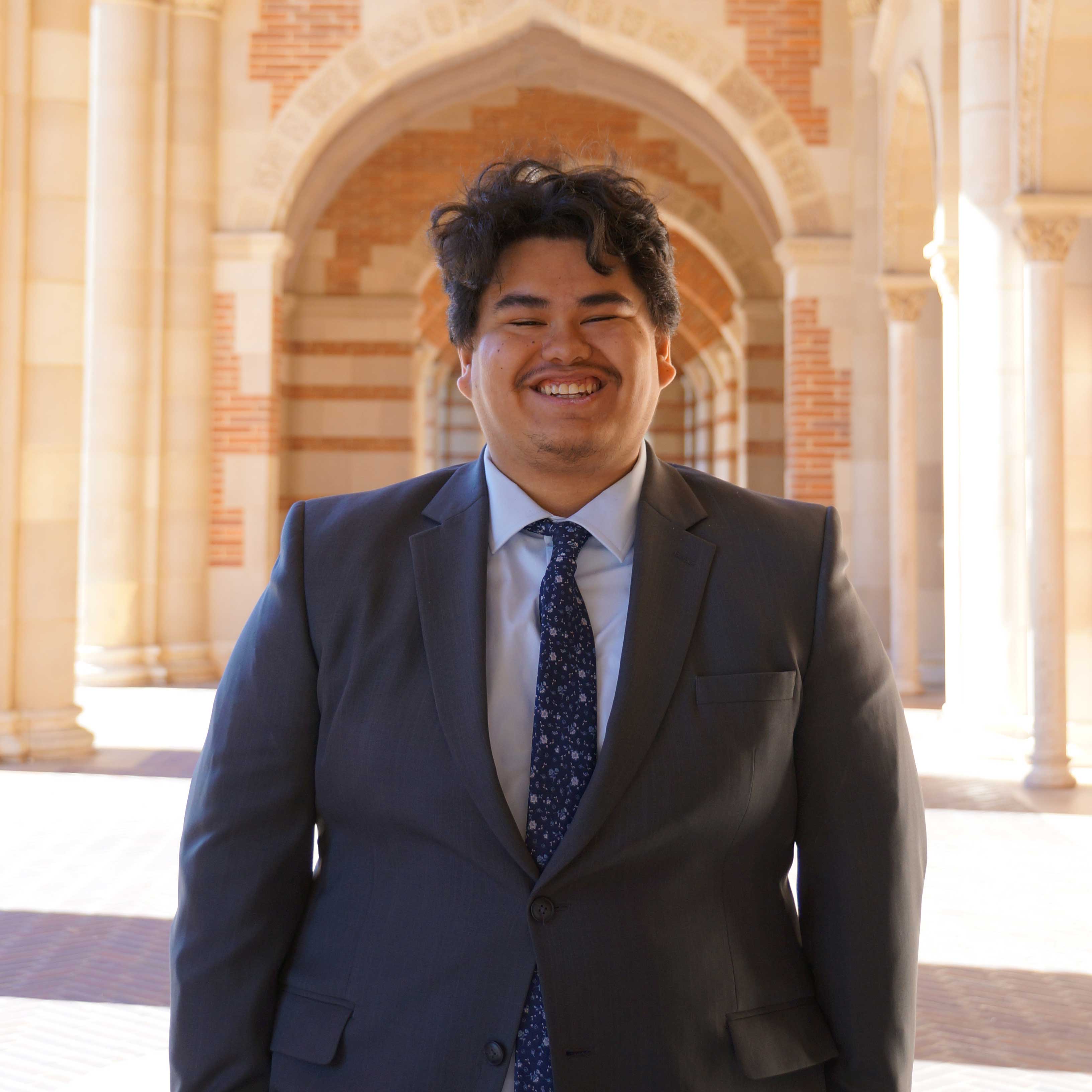 Portrait of Bryce Trevino standing underneath the arches of the front entrance of Royce Hall