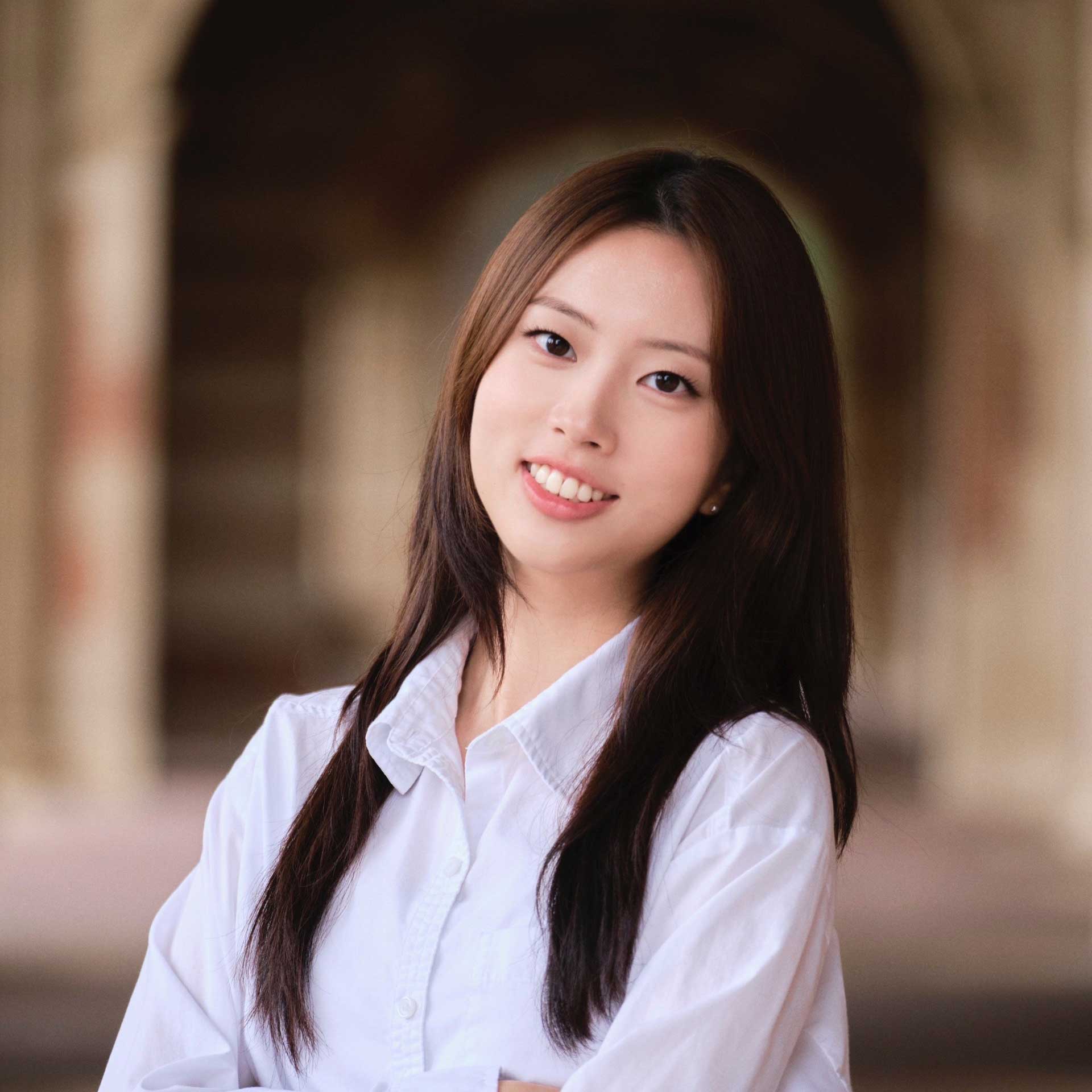 Portrait of Hyein Kang standing in front of a blurred photo of the arches at the front of Royce Hall