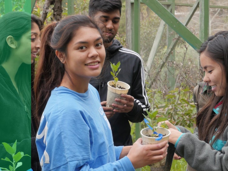 A student volunteer working with plants smiles at the camera. 