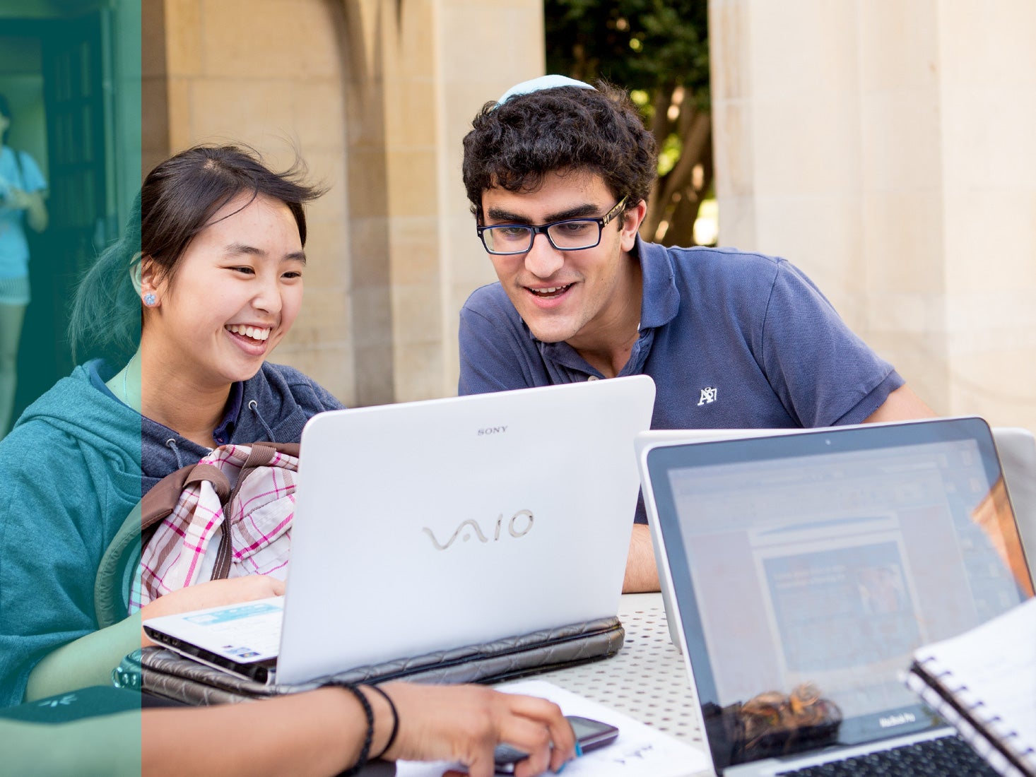 Several students study and have fun at an outdoor table.