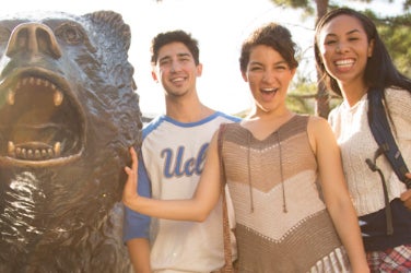 Students smile next to The Bruin statue.