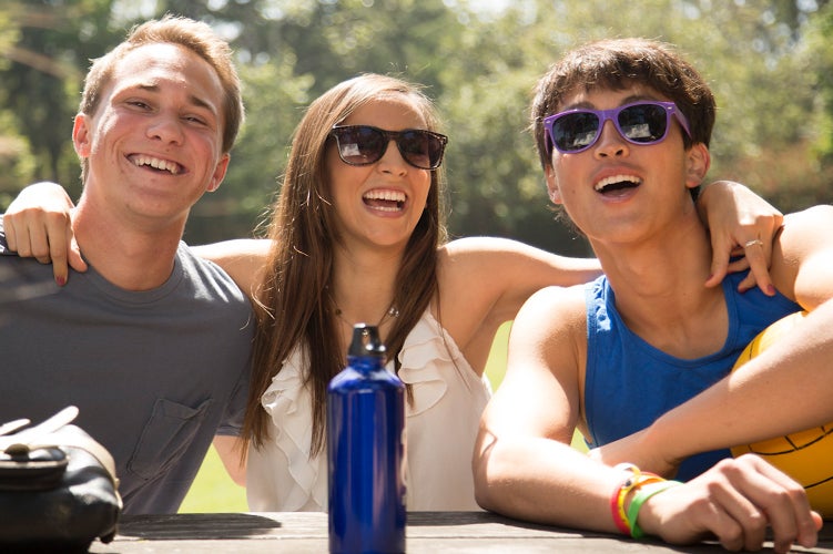 Three students enjoy each other’s company at an outdoor table.