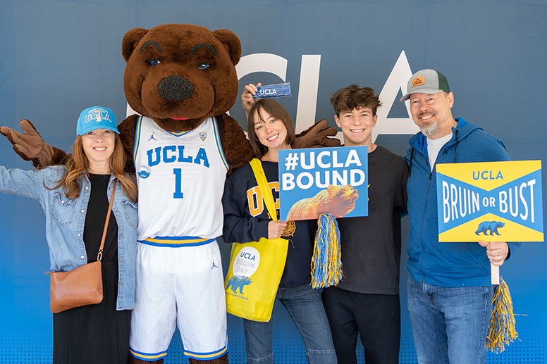 Two UCLA-bound students smile as they pose with their parents and Joe Bruin at Bruin Day.