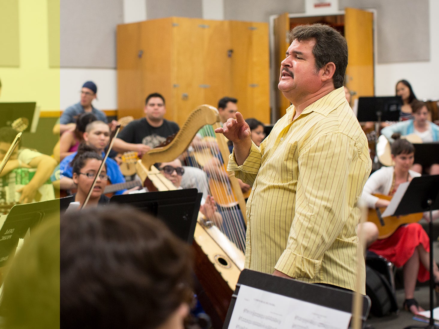 Arranger, director, instructor and musician Jesús Guzmán leads students in an orchestra.