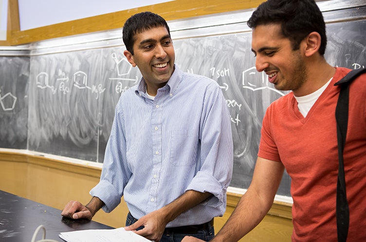 Professor Neil Garg shares a laugh with a student in his classroom.