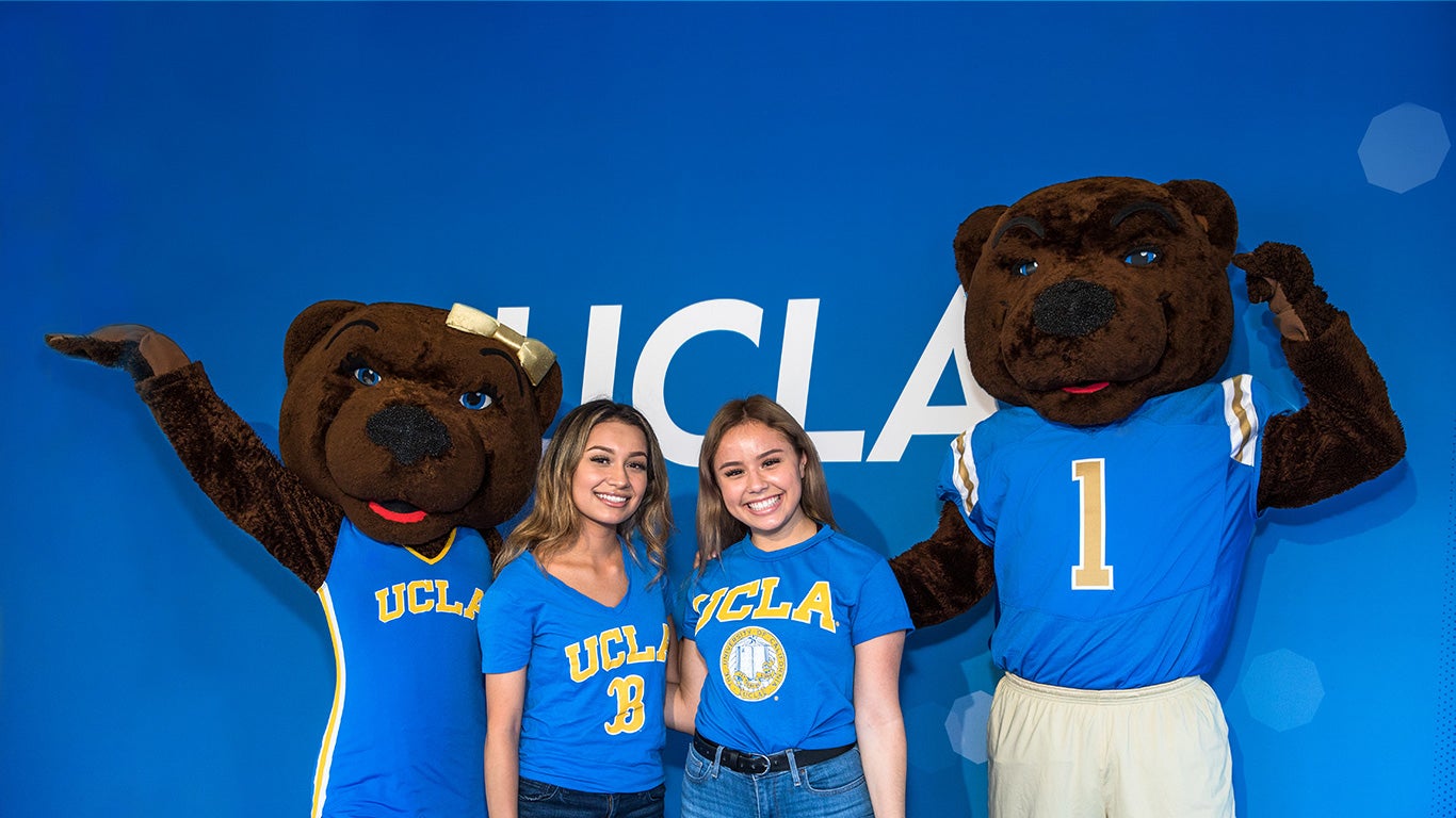 UCLA mascots Joe and Josie Bruin pose for a picture with two smiling students.