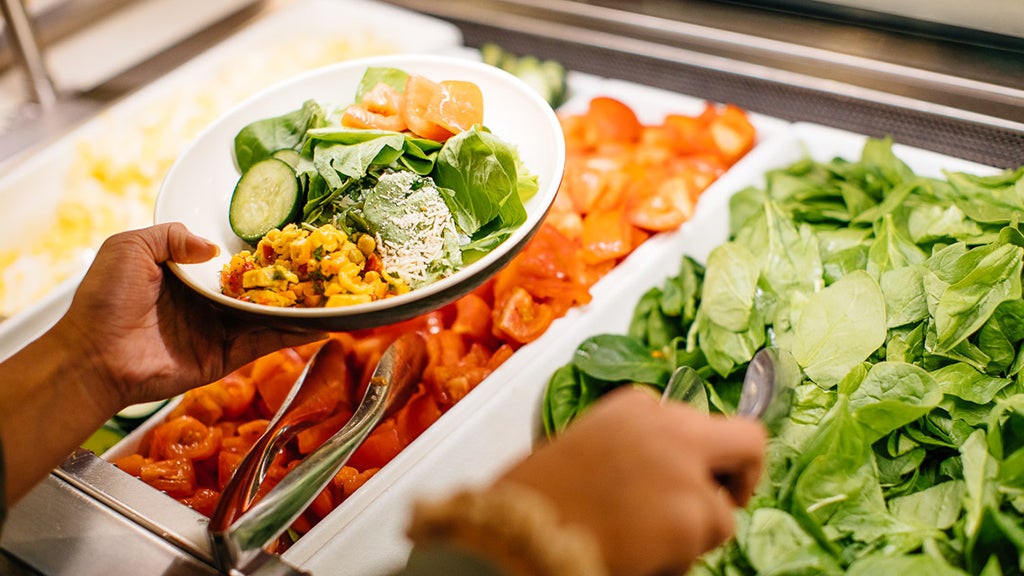 A student puts together a plate of food at a self-serve bar at Feast at Rieber.